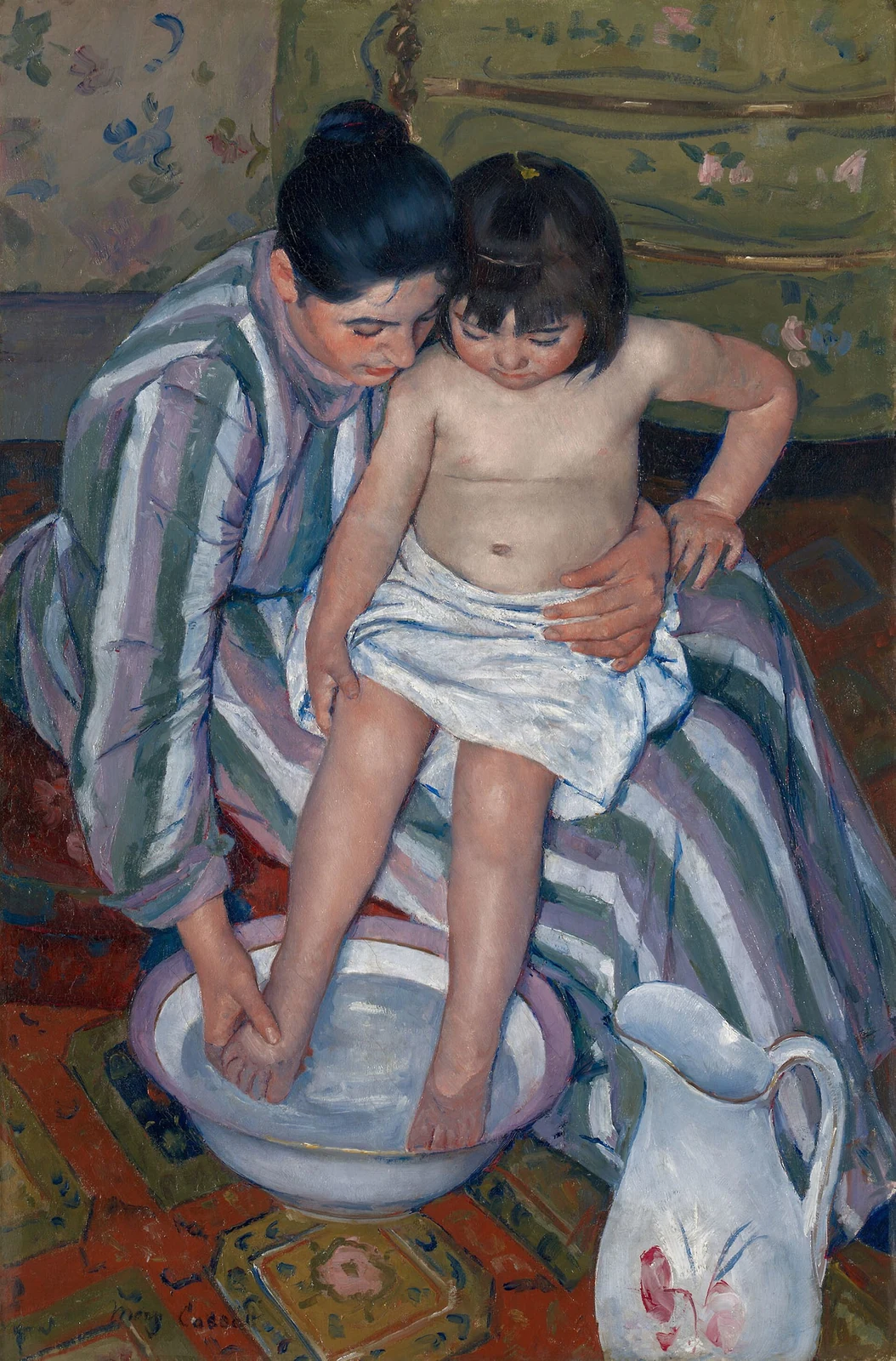 A woman steadies a child on her lap while washing the child’s foot, surrounded by striped fabric and patterned flooring.